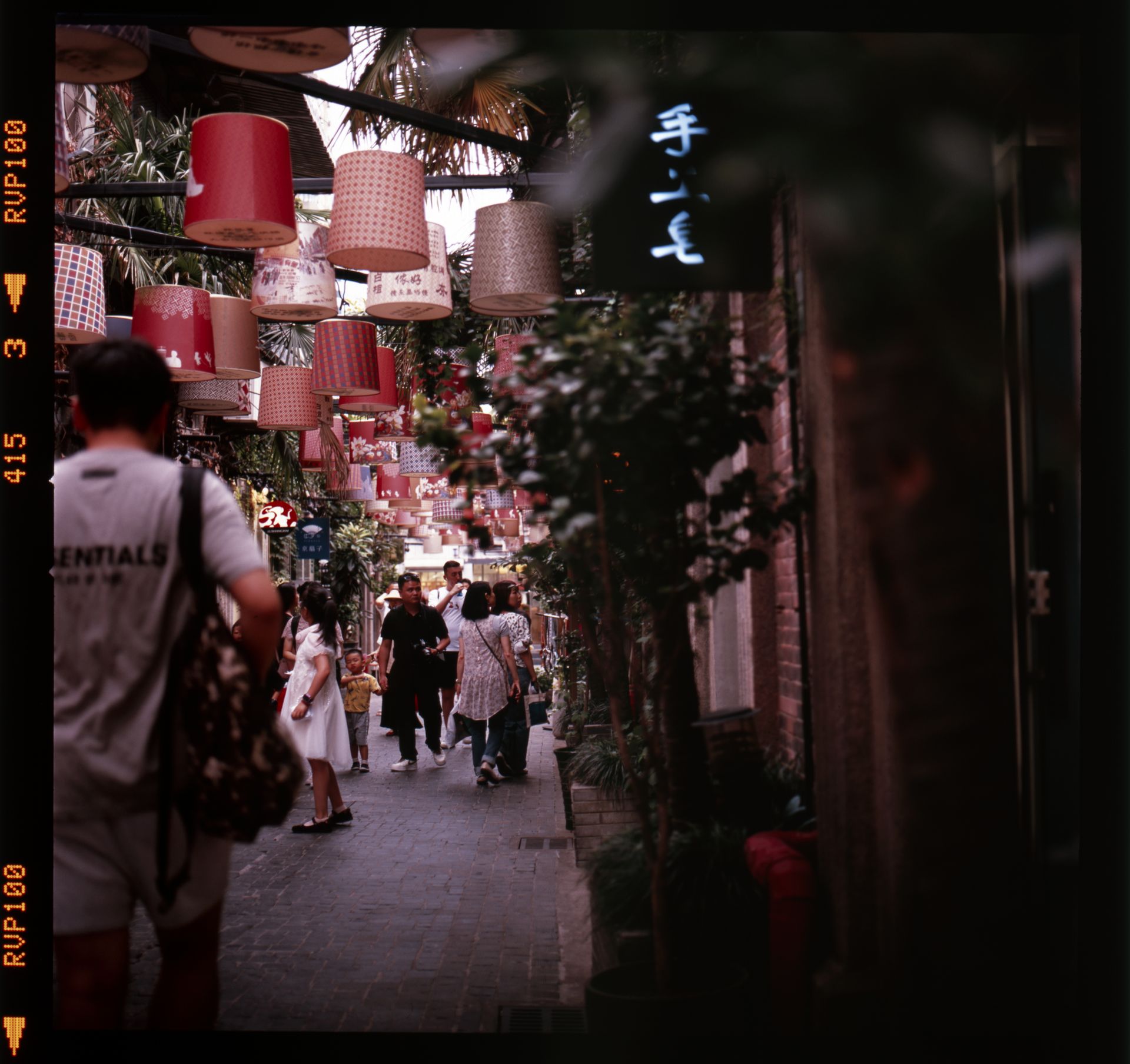 Colorful lanterns decorate a lively street in Tianzifang, Shanghai, vibrant with people.