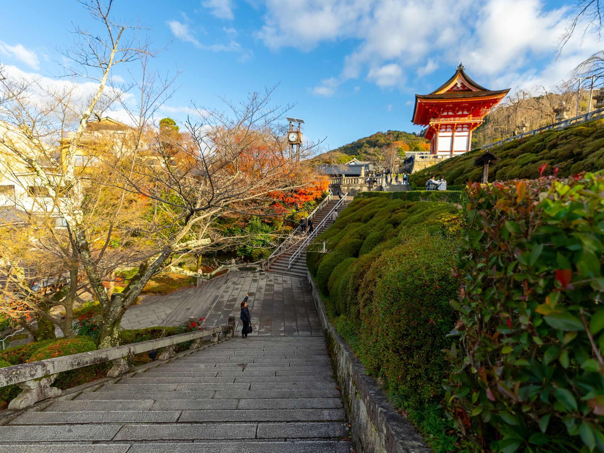 A picturesque view of Kiyomizu-dera temple in Kyoto during autumn with vibrant foliage and a clear blue sky.