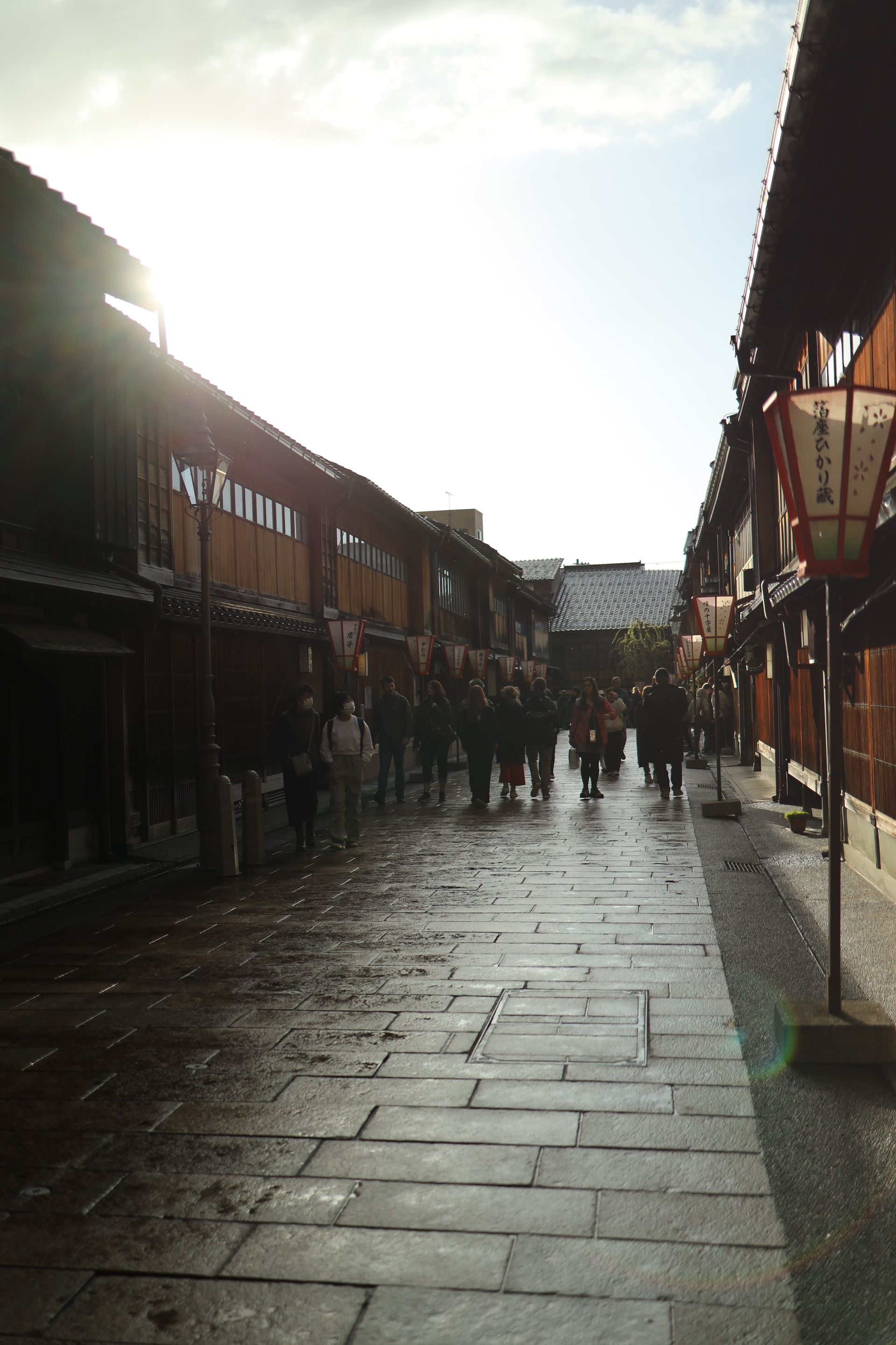 People walking on a traditional street in Gion, Kyoto under the afternoon sun.