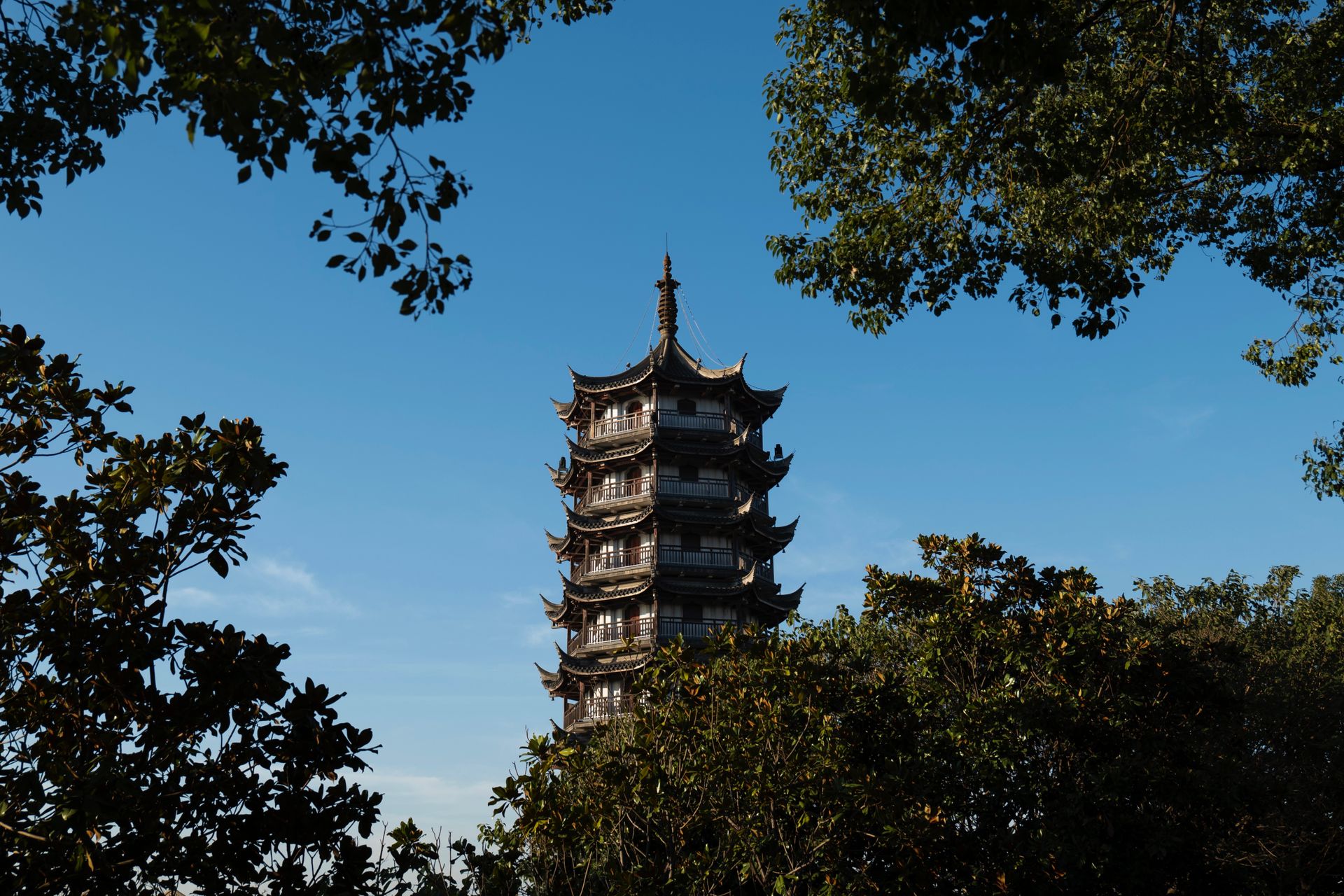 Scenic view of Longhua Pagoda in Shanghai framed by trees under a clear blue sky.