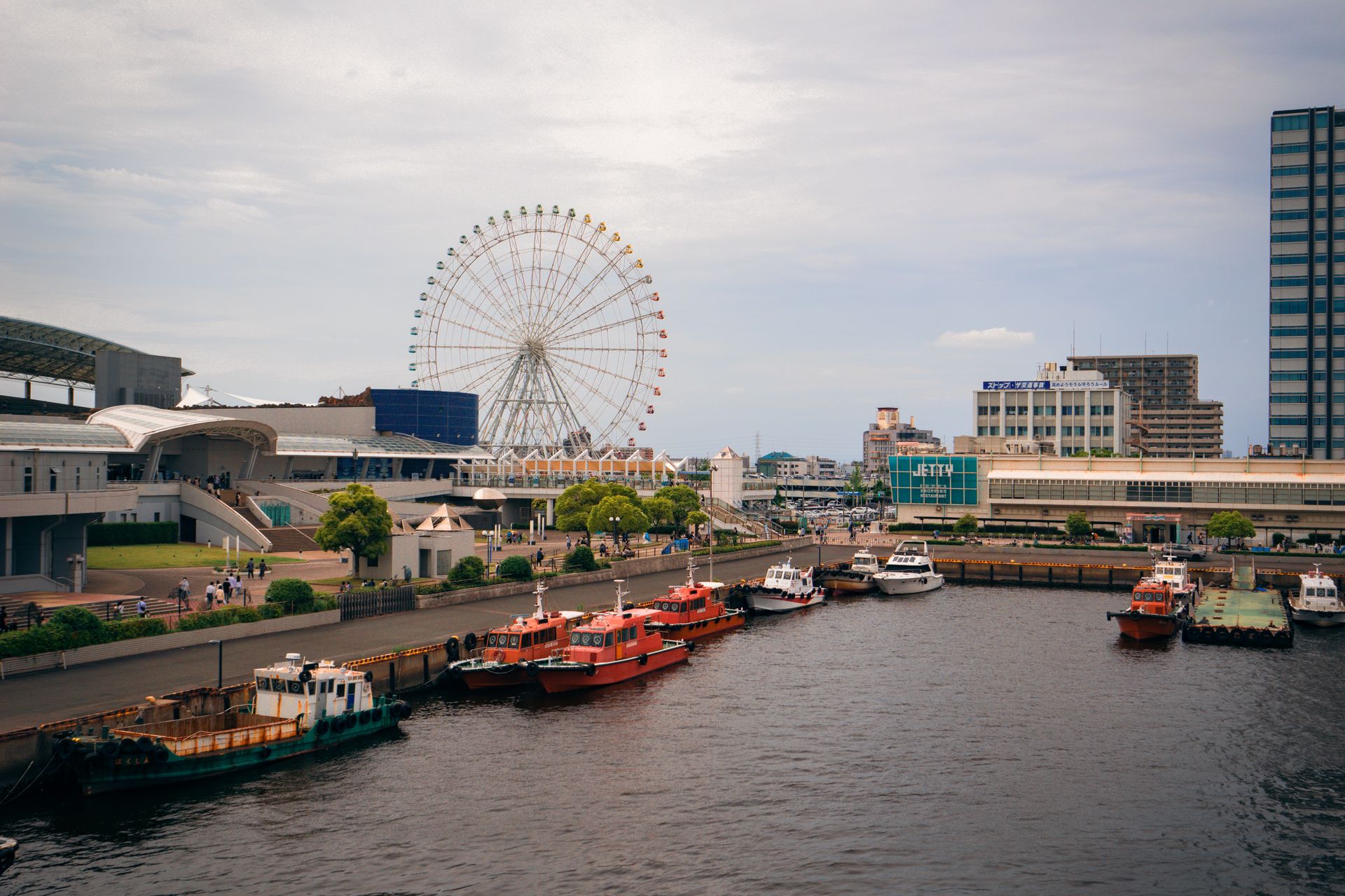 名古屋港浮码头边停着巡逻船与游艇，后方是摩天轮