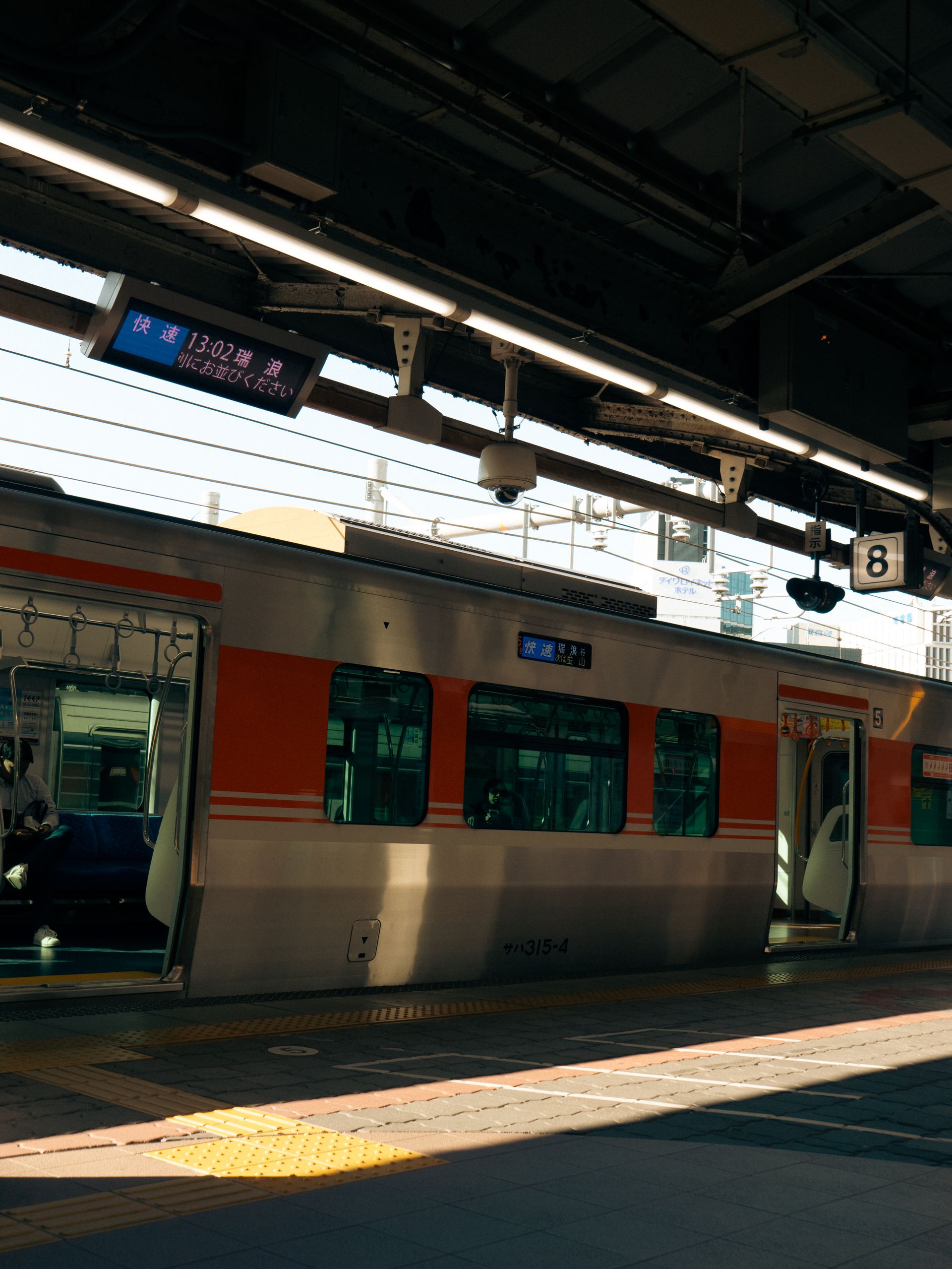 Urban scene capturing a train at Nagoya Station platform during the day.