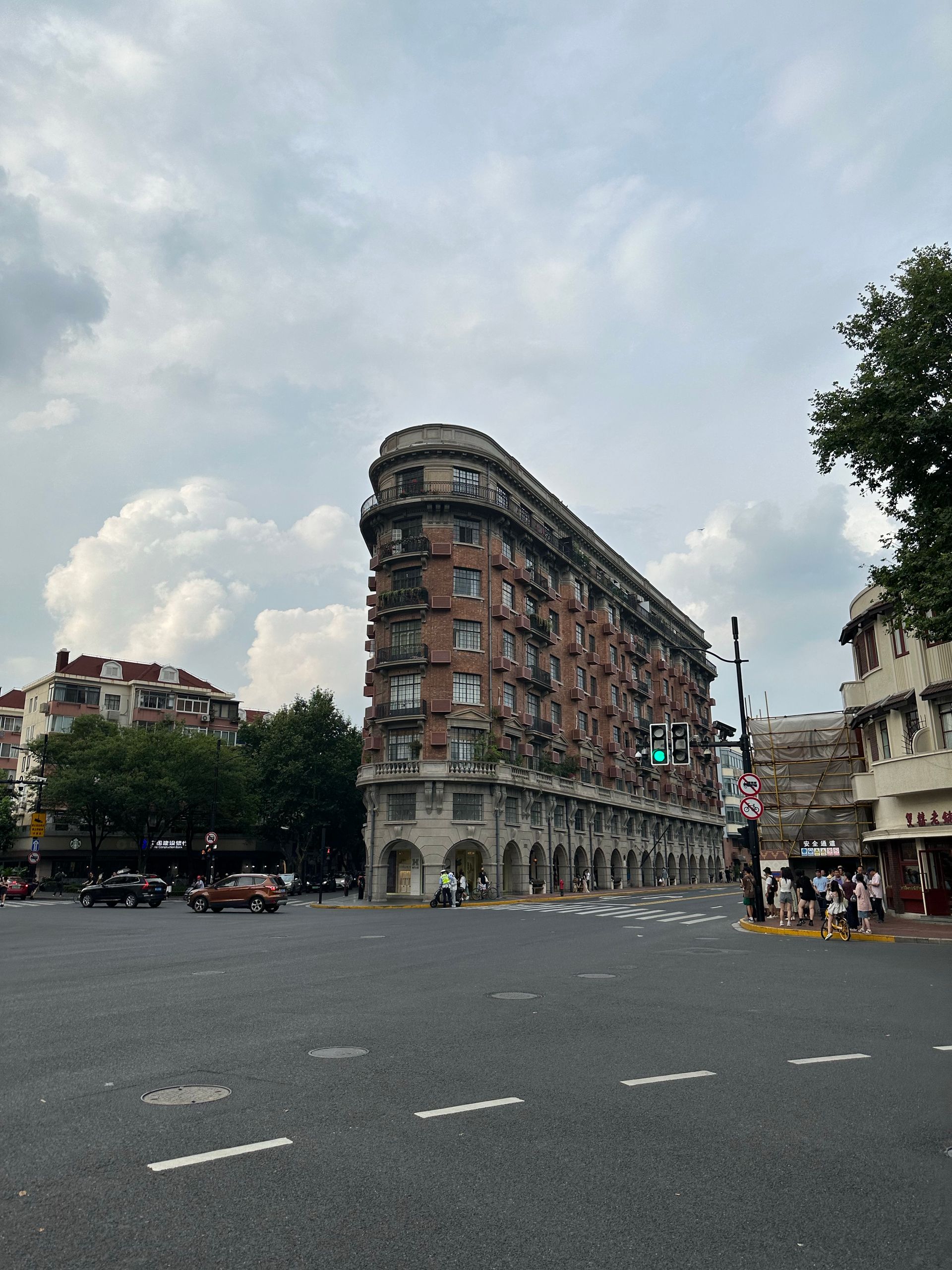 Wukang Building in Shanghai at a crossroad on a cloudy day, showcasing historic architecture.