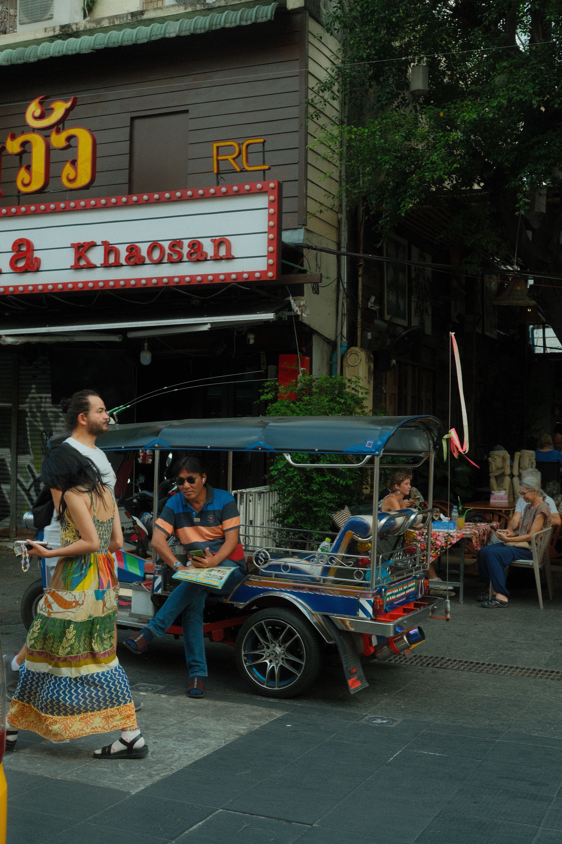 Vibrant street life on Khao San Road with people and a traditional rickshaw, capturing urban vibrancy.
