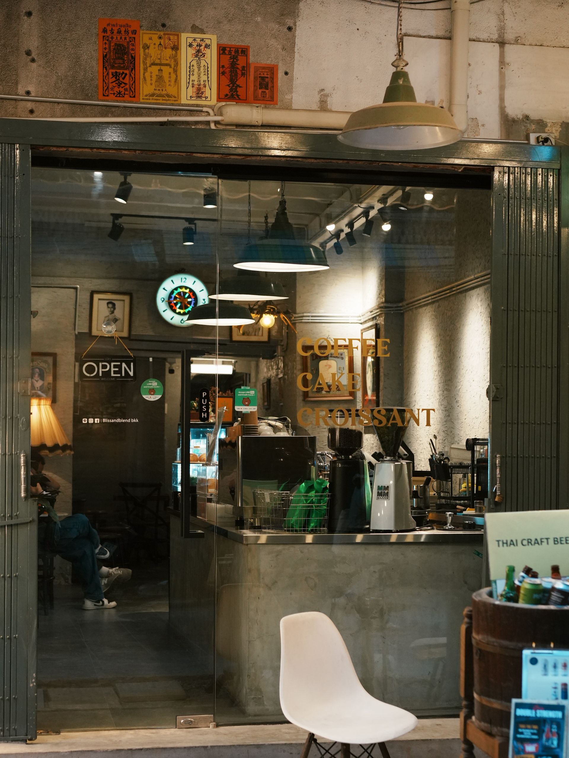 A warm and inviting coffee shop entrance in Bangkok at night.
