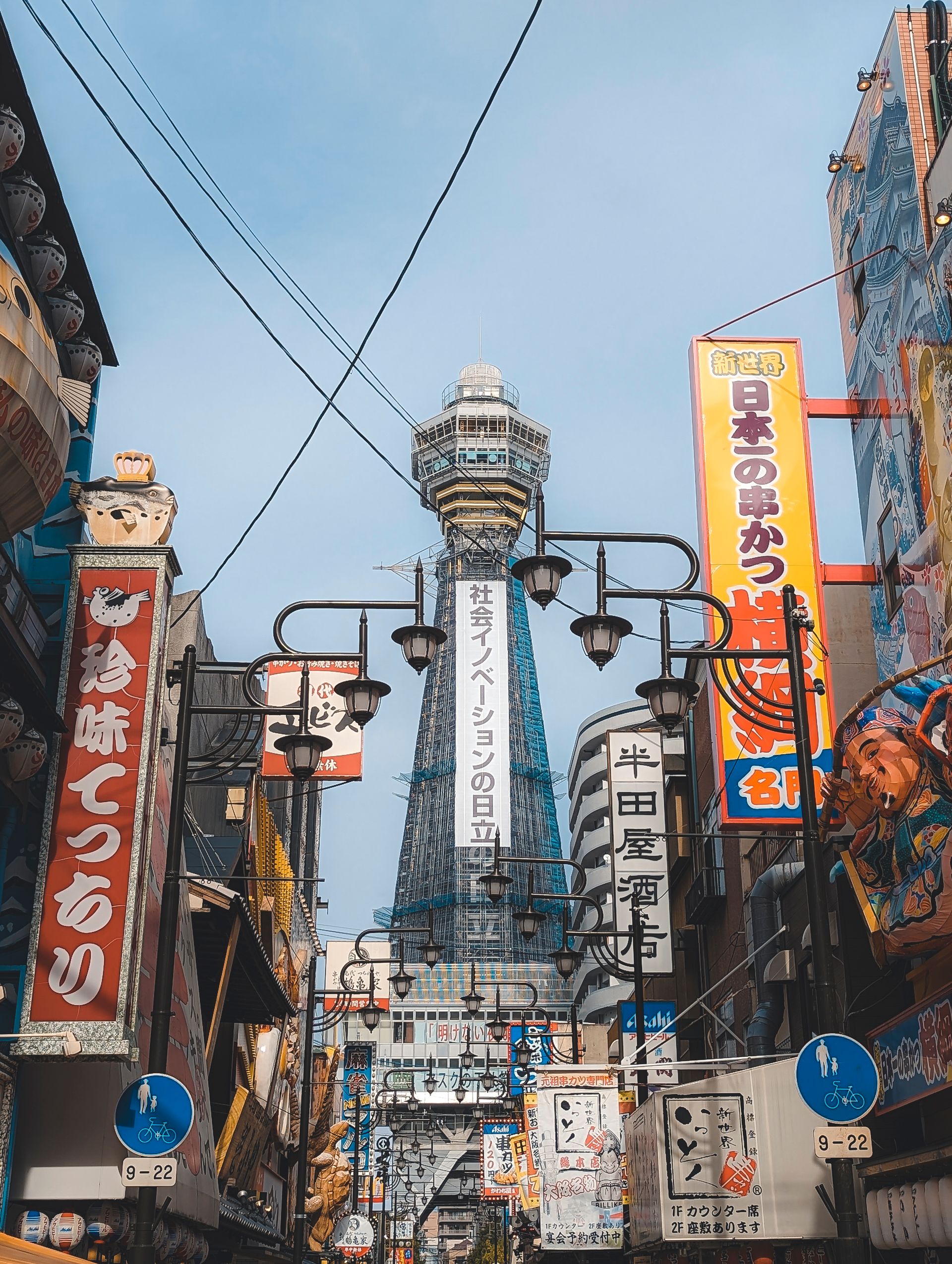 Colorful street scene in Osaka, Japan featuring Tsutenkaku Tower surrounded by vibrant signage.