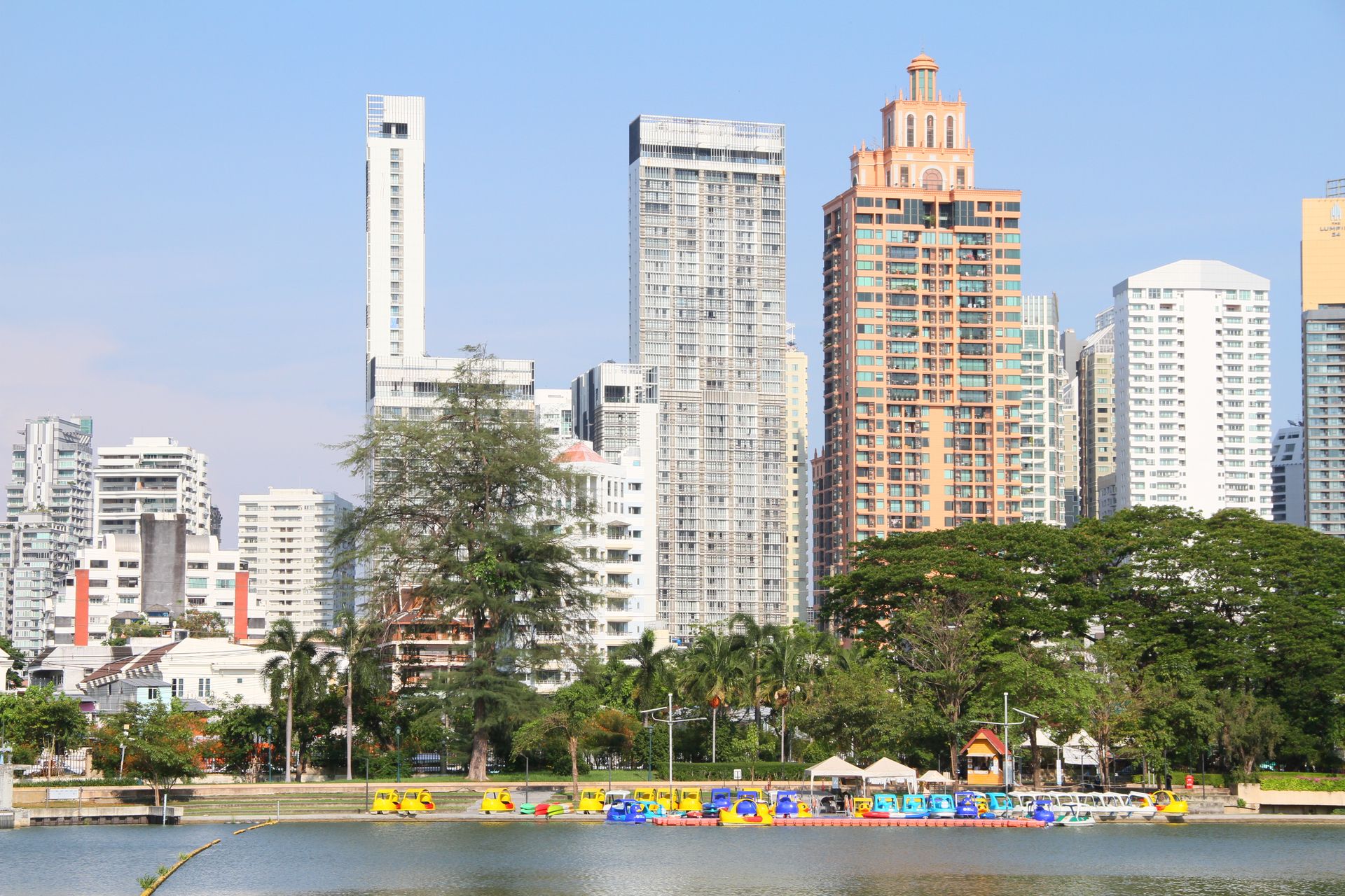 A vibrant cityscape featuring modern high-rise buildings by a lake on a clear day.