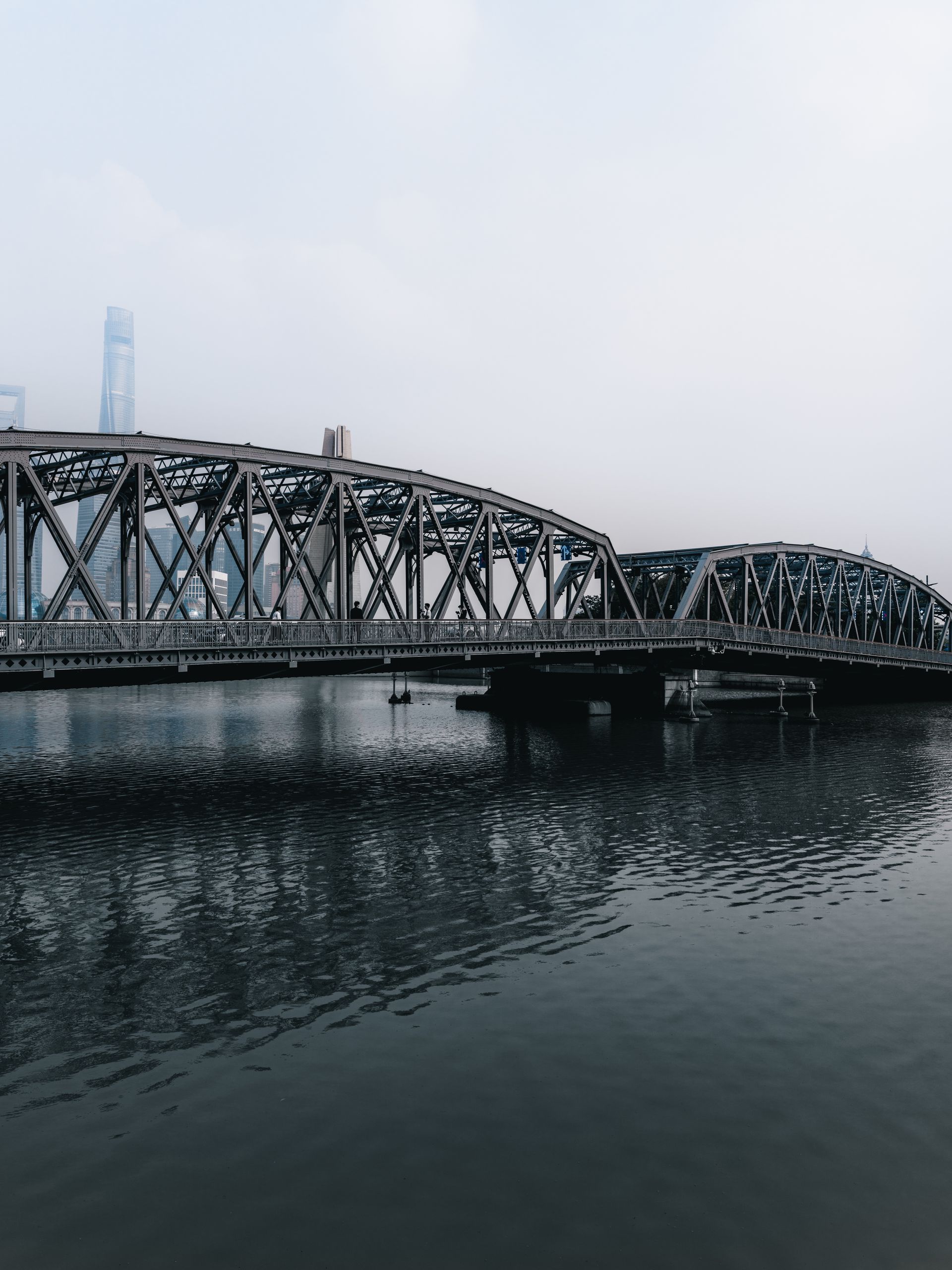 Iconic Waibaidu Bridge spanning Suzhou Creek with Shanghai skyline in background.