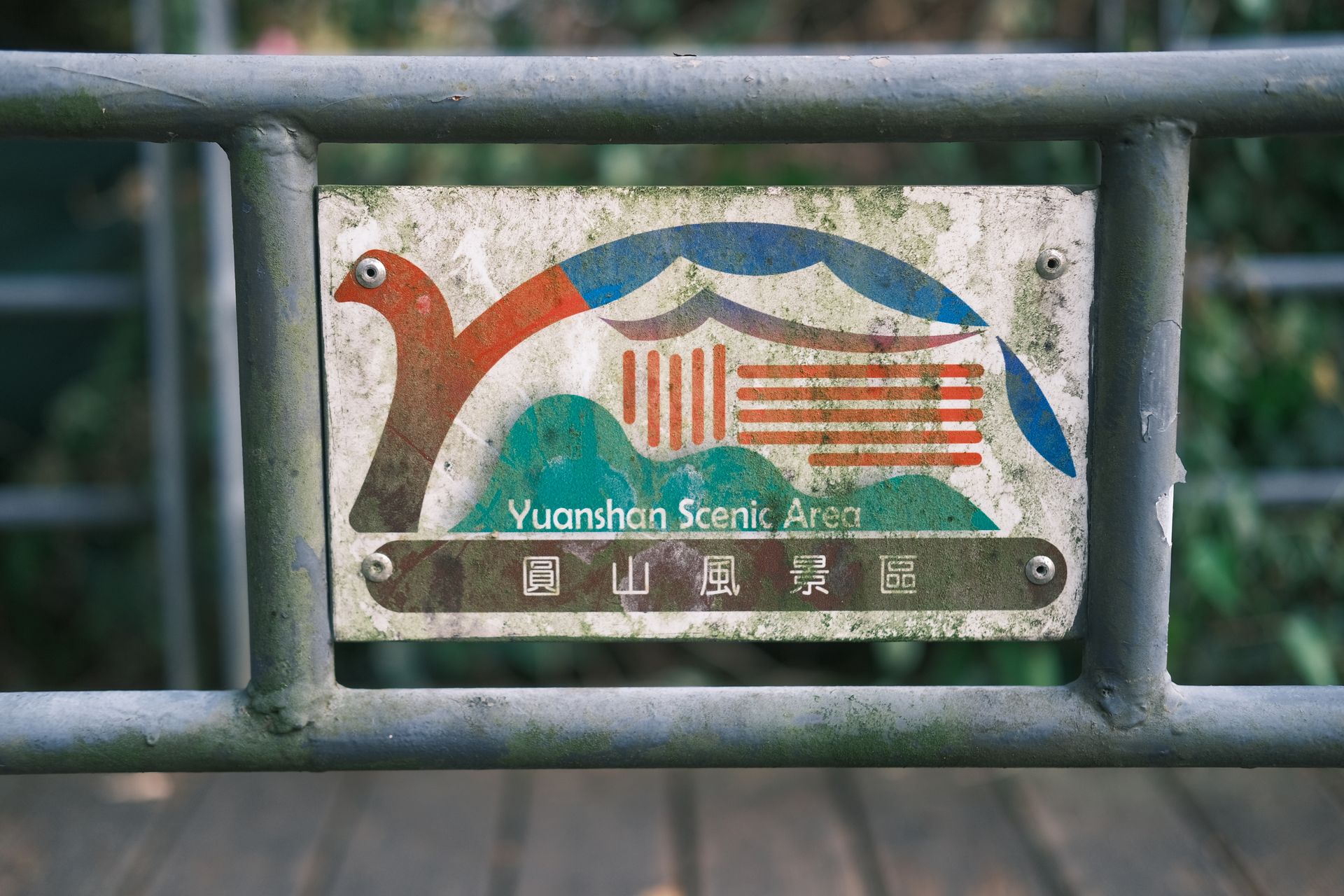 固定在栏杆上的圓山風景區告示牌，红绿蓝图案已经褪色