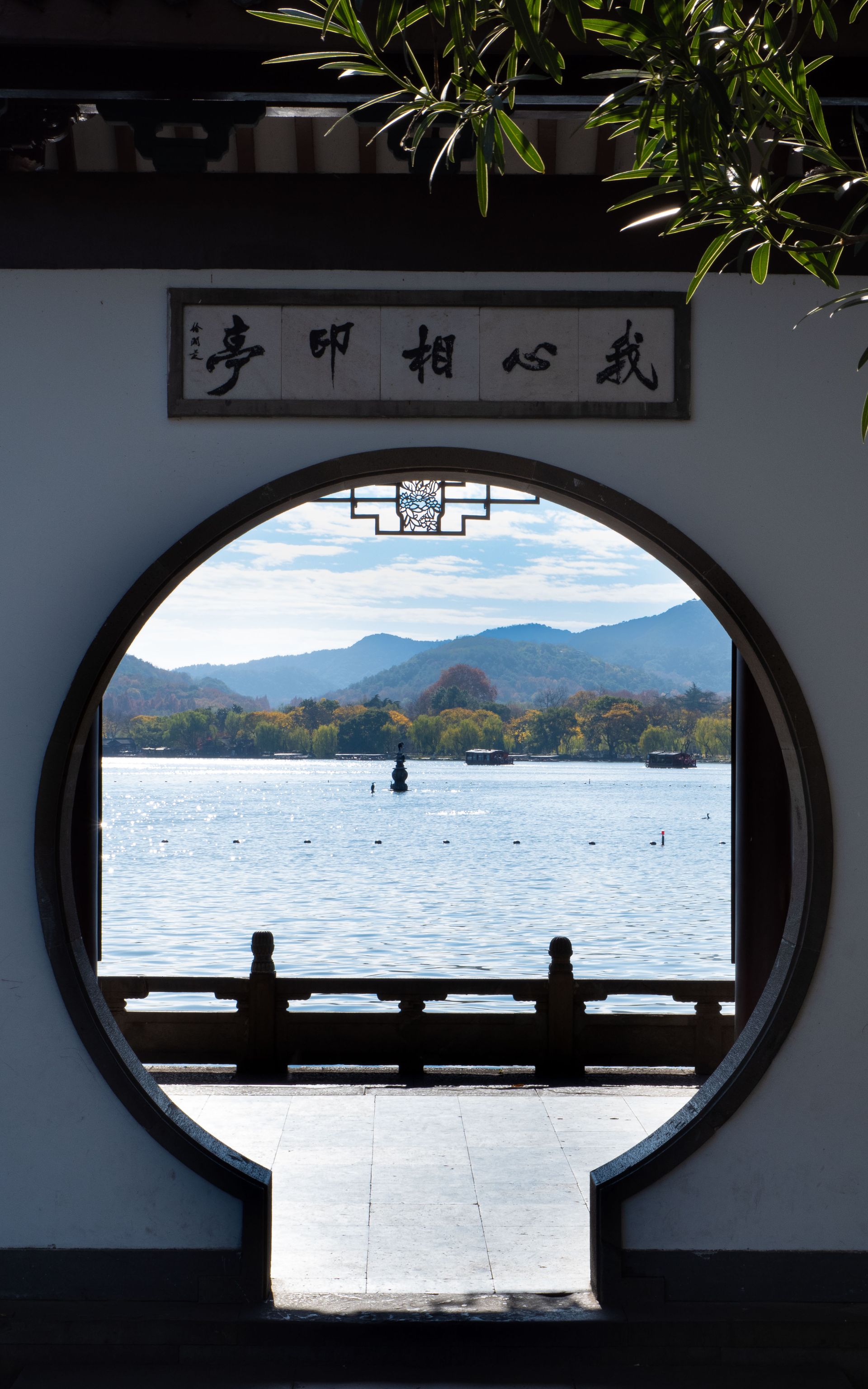 Scenic view of a lake through a circular doorway with distant hills and clear skies.