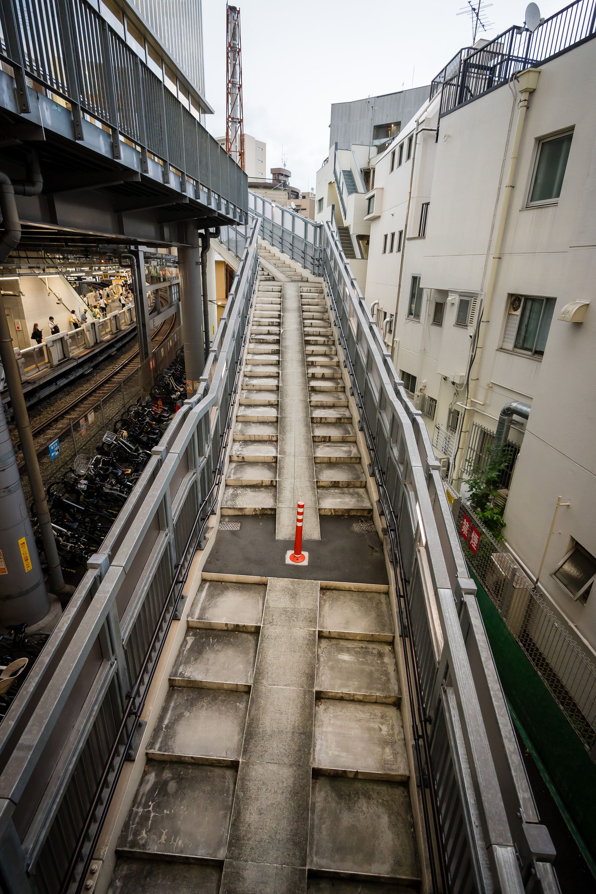 Concrete stairway in a bustling Japanese cityscape with modern architecture.