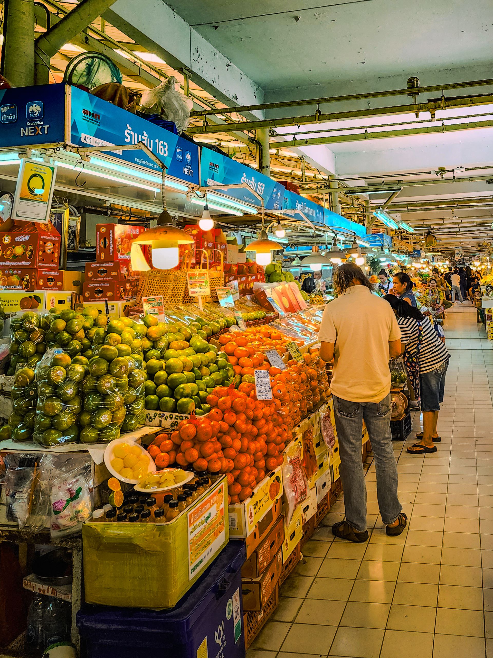 Explore the dynamic atmosphere of a bustling Bangkok market with colorful tropical fruits on display.