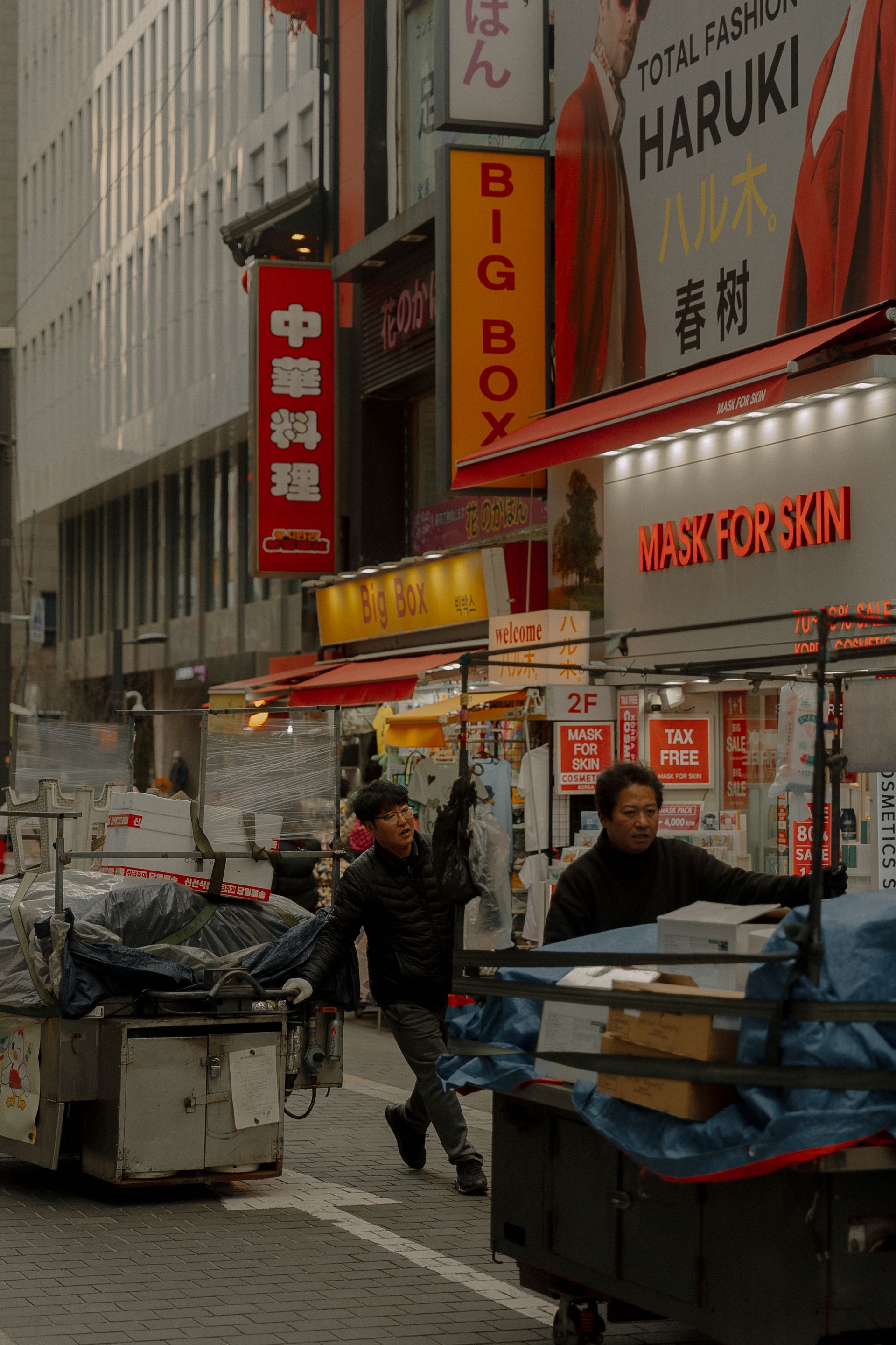 Men with trash bins on a street in Tokyo.