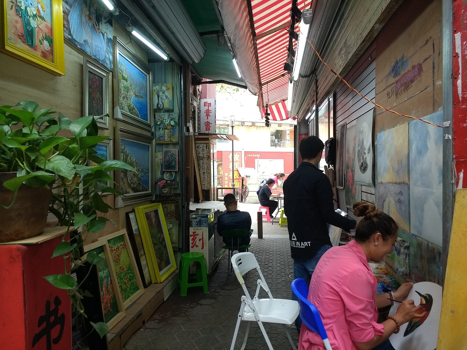 Artists painting canvases inside Dafen Oil Painting Village.