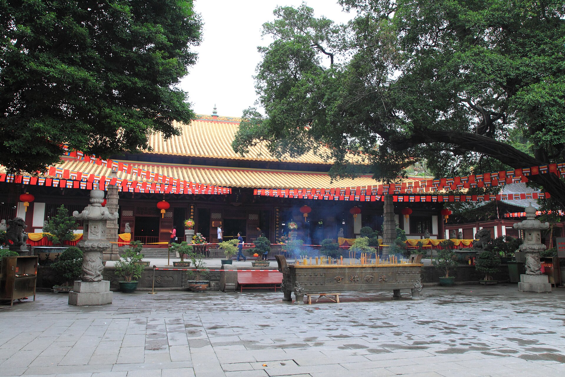 黄琉璃瓦重檐大殿前立着大型铜香炉，炉里燃着香、青烟往上走，炉身可见「光孝寺」字样，两旁是石塔与红灯笼