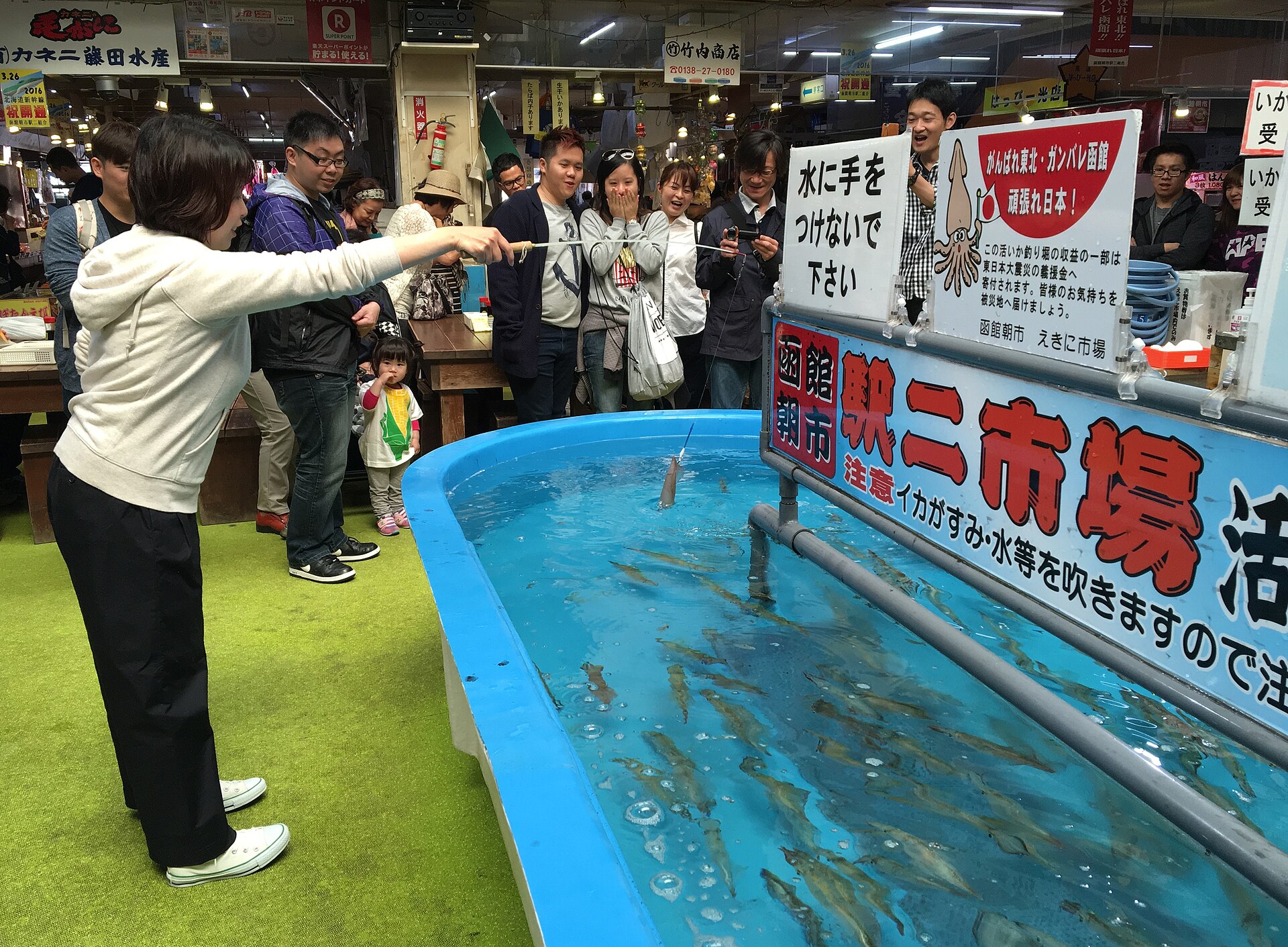 Spectators react with laughter and excitement as an angler snags a live squid at the Hakodate Asaichi (Hakodate Morning Market).