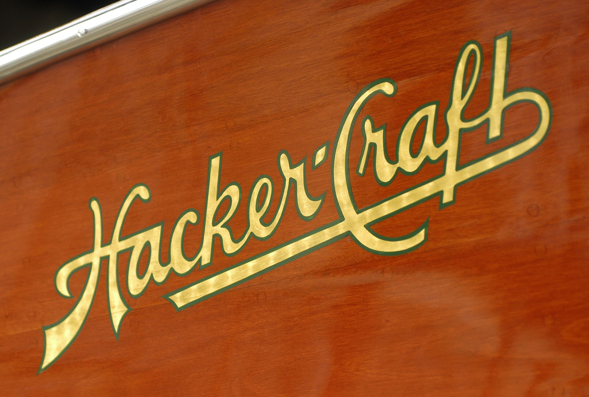 The Hacker logo hand-painted in gold leaf on the side of a mahogany runabout